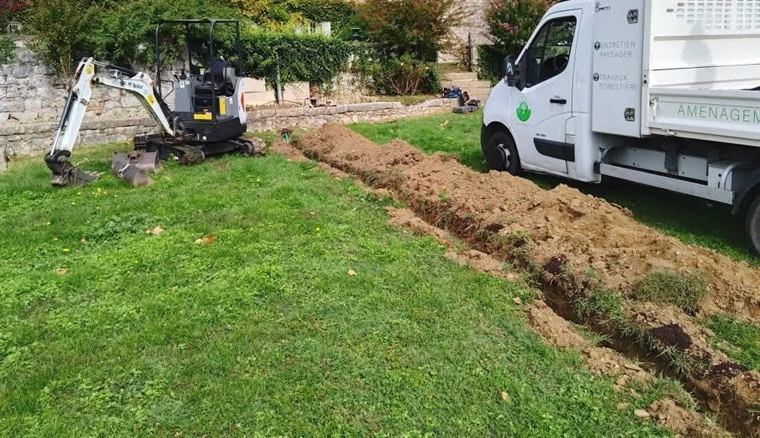 Mini-pelle creusant une tranchée dans une pelouse